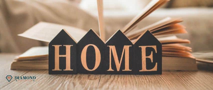 A book and a wooden sign that says "home" on a coffee table.