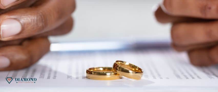 Two sets of a hands folded over divorce documents with wedding rings in the center.
