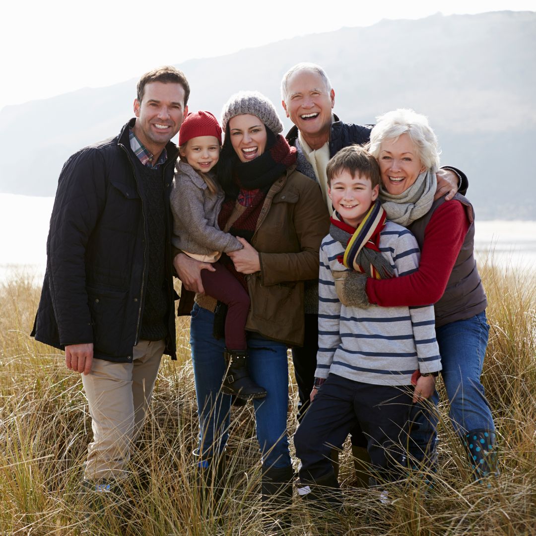 A family posing for a portrait in a field next to a lake.